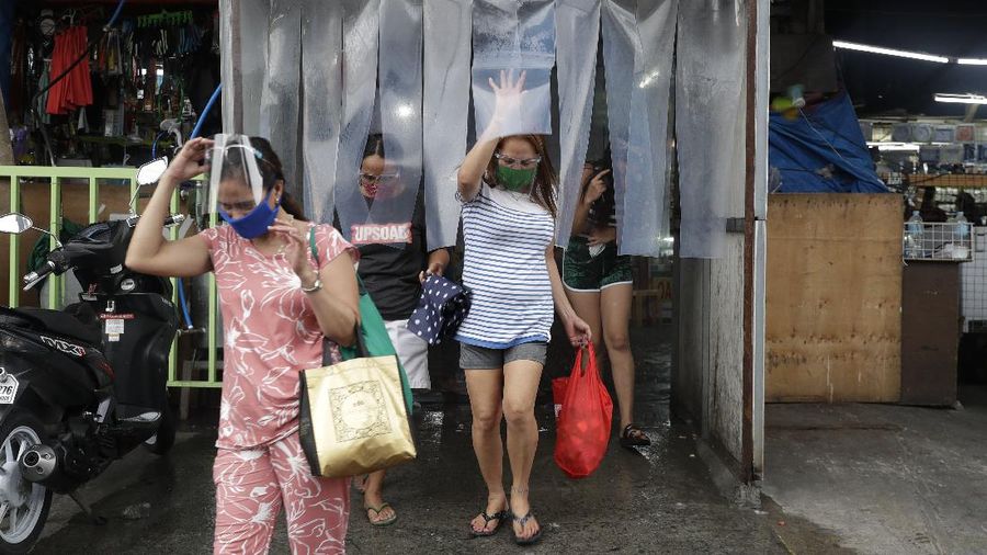 Police officers wearing protective gear carry a checkpoint sign on a roadway Tuesday, Aug. 4, 2020, outside Manila, Philippines, as the capital is placed on another lockdown in the hopes of controlling the surge of coronavirus cases. Commuter trains, buses and other public vehicles stayed off the main roads of the Philippine capital Tuesday and police were again staffing checkpoints to restrict public travel. (AP Photo/Aaron Favila)