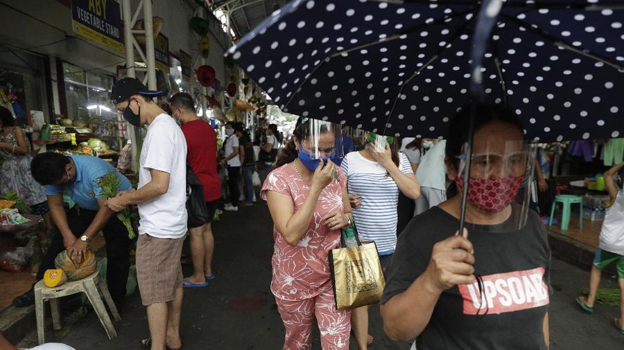 Police officers wearing protective gear carry a checkpoint sign on a roadway Tuesday, Aug. 4, 2020, outside Manila, Philippines, as the capital is placed on another lockdown in the hopes of controlling the surge of coronavirus cases. Commuter trains, buses and other public vehicles stayed off the main roads of the Philippine capital Tuesday and police were again staffing checkpoints to restrict public travel. (AP Photo/Aaron Favila)