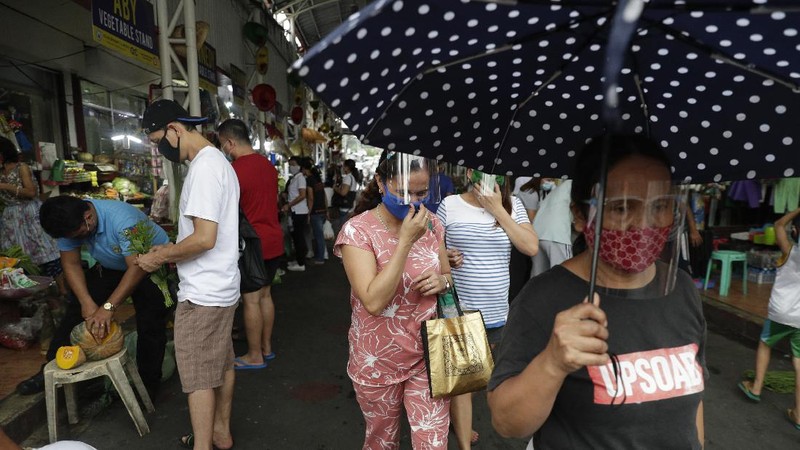 Police officers wearing protective gear carry a checkpoint sign on a roadway Tuesday, Aug. 4, 2020, outside Manila, Philippines, as the capital is placed on another lockdown in the hopes of controlling the surge of coronavirus cases. Commuter trains, buses and other public vehicles stayed off the main roads of the Philippine capital Tuesday and police were again staffing checkpoints to restrict public travel. (AP Photo/Aaron Favila)