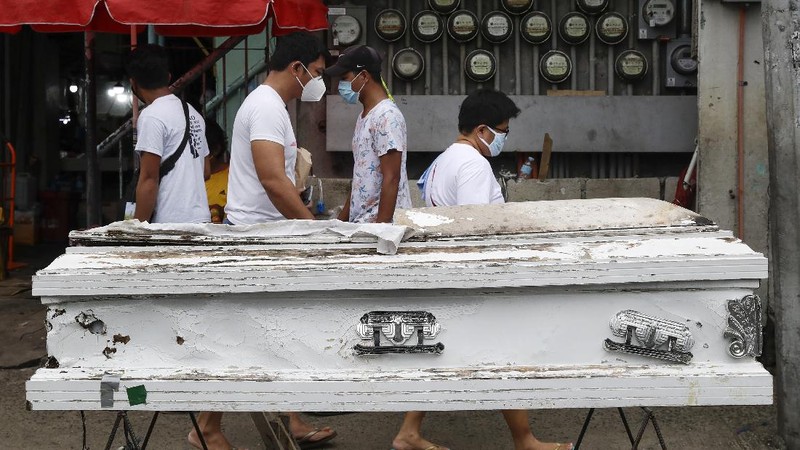 Police officers wearing protective gear carry a checkpoint sign on a roadway Tuesday, Aug. 4, 2020, outside Manila, Philippines, as the capital is placed on another lockdown in the hopes of controlling the surge of coronavirus cases. Commuter trains, buses and other public vehicles stayed off the main roads of the Philippine capital Tuesday and police were again staffing checkpoints to restrict public travel. (AP Photo/Aaron Favila)