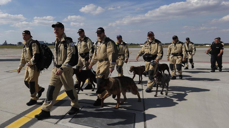 Anggota tim SAR Ceko beserta anjing pelacak berjalan menaiki pesawat di bandara Vaclav Havel di Praha, Rabu (5/8/2020). Republik Ceko mengirimkan sekitar 37 personel dan lima ekor anjing pelacak untuk membantu pencarian korban ledakan dahsyat di Beirut, Lebanon. (AP Photo/Petr David Josek)