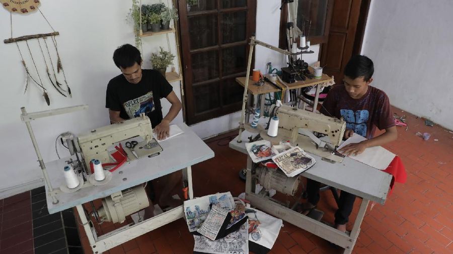Pengrajin saat menjahit tas kantongan berbahan kanvas organik/katun yang diproduksi menjadi sovenir khas Jakarta di Workshop AIU Craft, Jakarta Timur. (CNBC Indonesia/Muhammad Sabki)