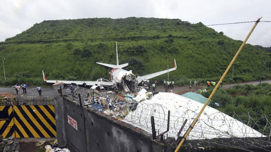 Officials stand by the debris of the Air India Express flight that skidded off a runway while landing in Kozhikode, Kerala state, India, Saturday, Aug. 8, 2020. The special evacuation flight bringing people home to India who had been trapped abroad because of the coronavirus skidded off the runway and split in two while landing in heavy rain killing more than a dozen people and injuring dozens more. (AP Photo/Shijith Sreedhar)