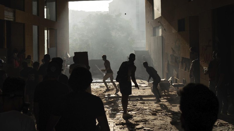 Anti-government protesters clash with riot police officers during a protest against the political elites and the government after this week's deadly explosion at Beirut port which devastated large parts of the capital in Beirut, Lebanon, Saturday, Aug. 8, 2020. (AP Photo/Hassan Ammar)