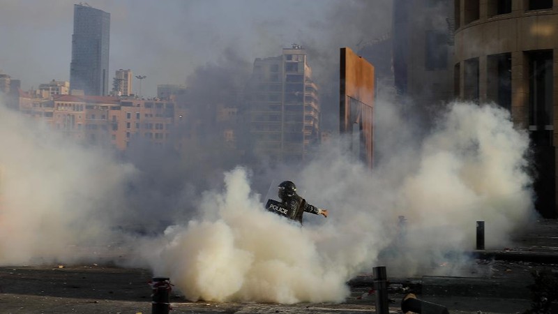 Anti-government protesters clash with riot police officers during a protest against the political elites and the government after this week's deadly explosion at Beirut port which devastated large parts of the capital in Beirut, Lebanon, Saturday, Aug. 8, 2020. (AP Photo/Hassan Ammar)