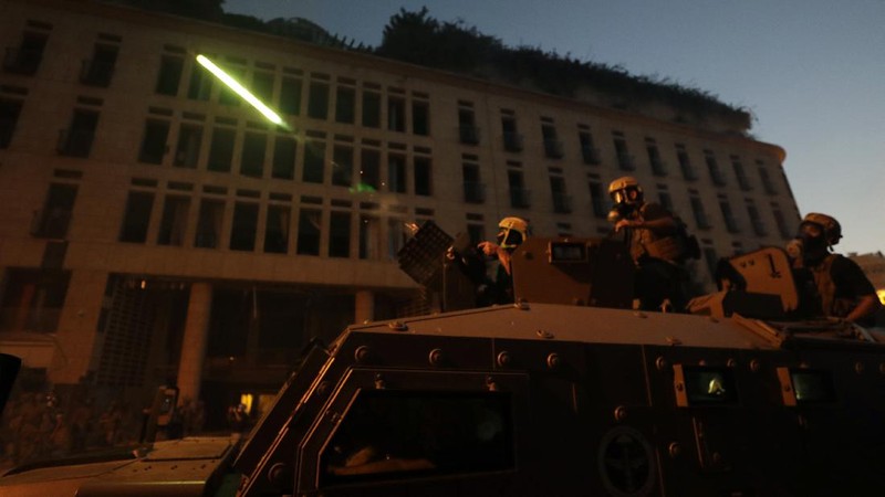 Anti-government protesters clash with riot police officers during a protest against the political elites and the government after this week's deadly explosion at Beirut port which devastated large parts of the capital in Beirut, Lebanon, Saturday, Aug. 8, 2020. (AP Photo/Hassan Ammar)