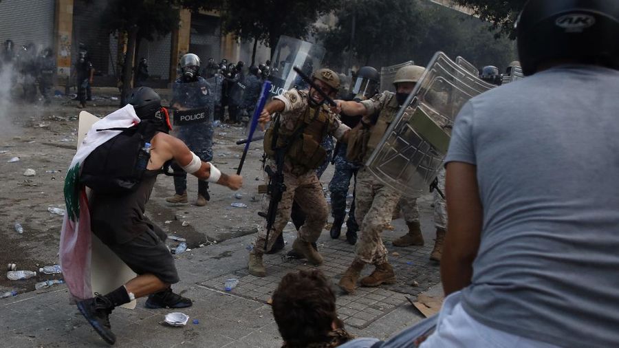 A protestor hits a Lebanese soldier with a baseball bat during clashes with police as part of a protest against the political elites and the government after this week's deadly explosion at Beirut port which devastated large parts of the capital in Beirut, Lebanon, Saturday, Aug. 8, 2020. (AP Photo/Thibault Camus)