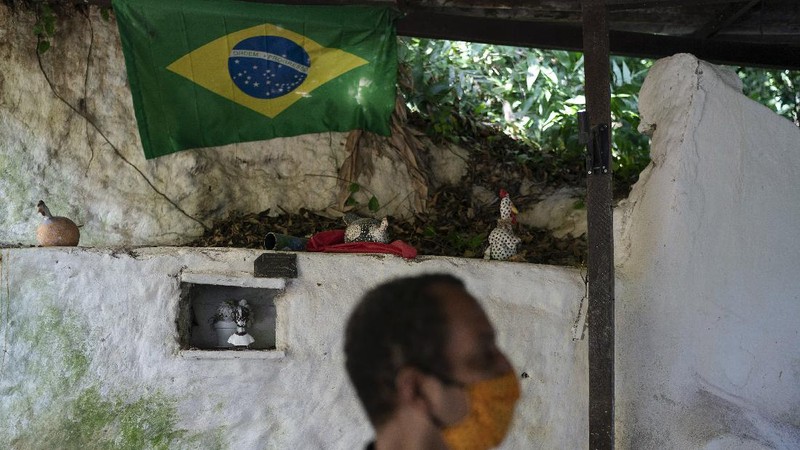 A man dressed in a Batman costume holds a sign with a message that reads in Portuguese: 