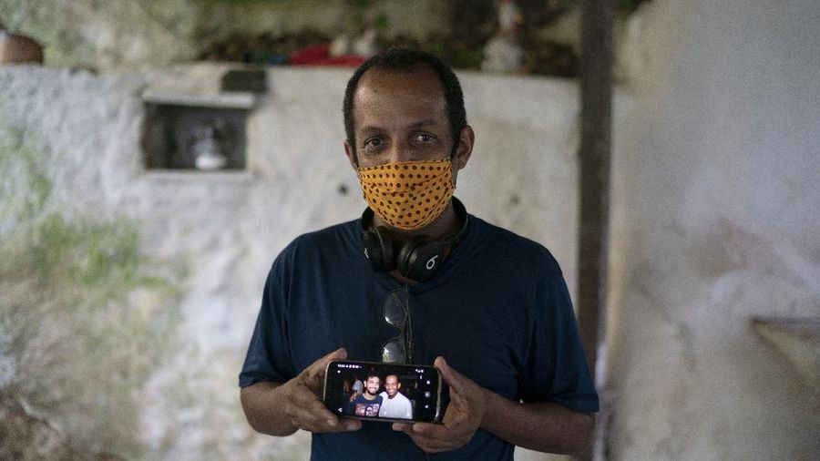 A man dressed in a Batman costume holds a sign with a message that reads in Portuguese: 