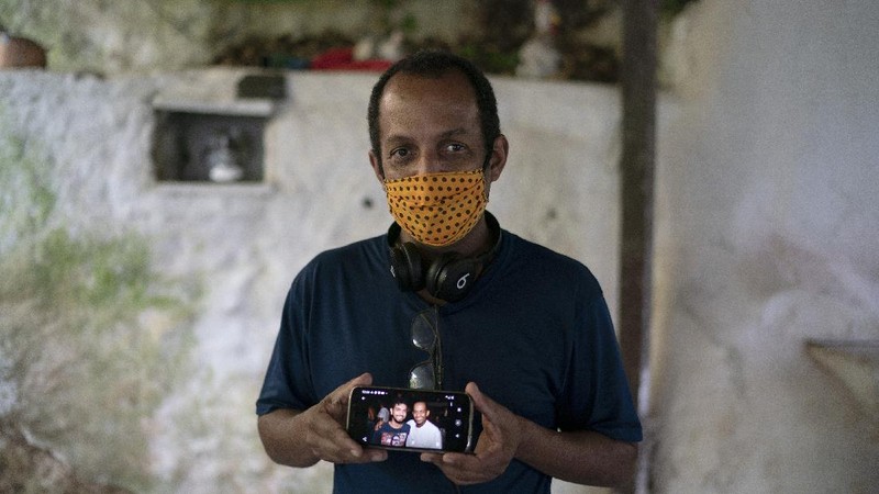 A man dressed in a Batman costume holds a sign with a message that reads in Portuguese: 