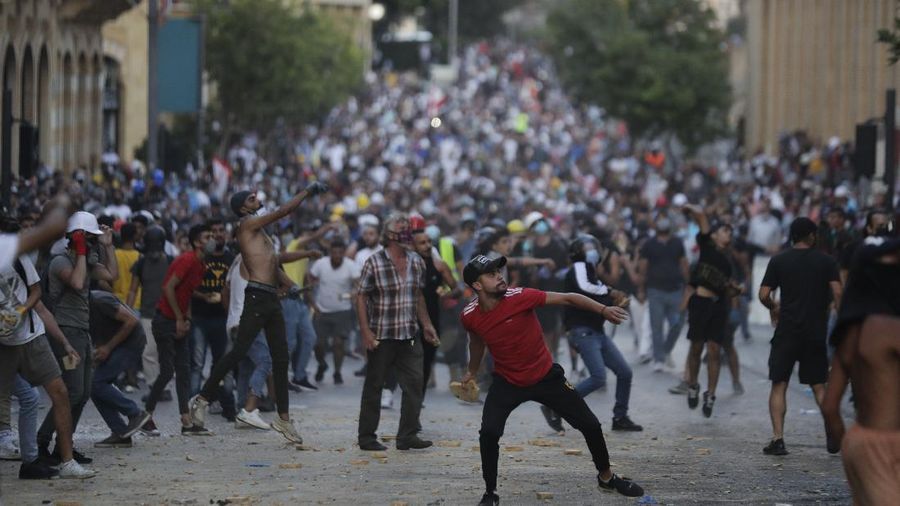 People throw stones during anti-government protest following Tuesday's massive explosion which devastated Beirut, Lebanon, Sunday, Aug. 9. 2020. (AP Photo/Hassan Ammar)