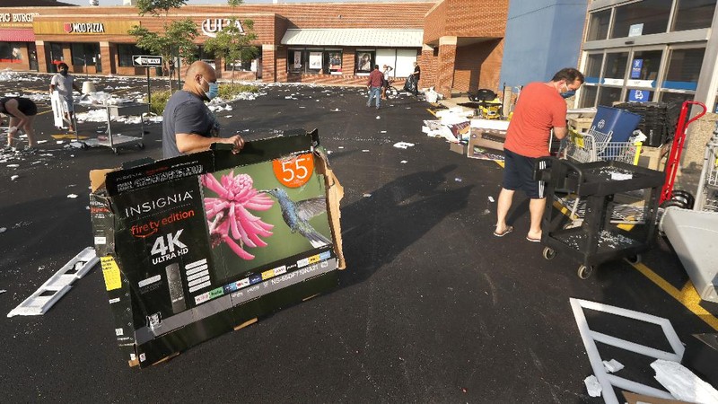 Kajal Dalal walks through her family's food and liquor store Monday, Aug. 10, 2020, after it was vandalized in downtown Chicago. Chicago’s police commissioner says more than 100 people were arrested following a night of looting and unrest that left several officers injured and caused damage in the city’s upscale Magnificent Mile shopping district and other parts of the city. (AP Photo/Charles Rex Arbogast)