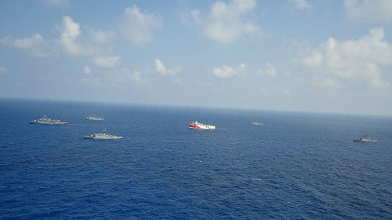 In this photo provided by the Turkish Defense Ministry, Turkey's research vessel, Oruc Reis, in red and white, is surrounded by Turkish navy vessels as it was heading in the west of Antalya on the Mediterranean, Turkey, Monday, Aug 10, 2020. Tension remains high between Greece and Turkey, whose warships are in the eastern Mediterranean where Turkey has sent a research vessel to carry out seismic research for energy resources in an area Greece says is on its continental shelf. (Turkish Defense Ministry via AP, Pool)