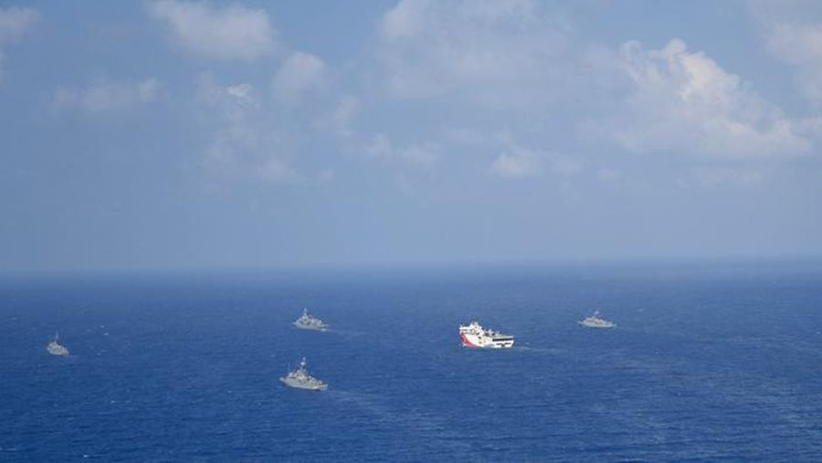 In this photo provided by the Turkish Defense Ministry, Turkey's research vessel, Oruc Reis, in red and white, is surrounded by Turkish navy vessels as it was heading in the west of Antalya on the Mediterranean, Turkey, Monday, Aug 10, 2020. Tension remains high between Greece and Turkey, whose warships are in the eastern Mediterranean where Turkey has sent a research vessel to carry out seismic research for energy resources in an area Greece says is on its continental shelf. (Turkish Defense Ministry via AP, Pool)