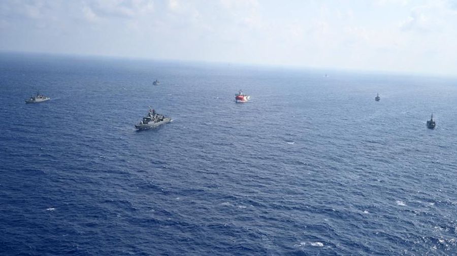 In this photo provided by the Turkish Defense Ministry, Turkey's research vessel, Oruc Reis, in red and white, is surrounded by Turkish navy vessels as it was heading in the west of Antalya on the Mediterranean, Turkey, Monday, Aug 10, 2020. Tension remains high between Greece and Turkey, whose warships are in the eastern Mediterranean where Turkey has sent a research vessel to carry out seismic research for energy resources in an area Greece says is on its continental shelf. (Turkish Defense Ministry via AP, Pool)