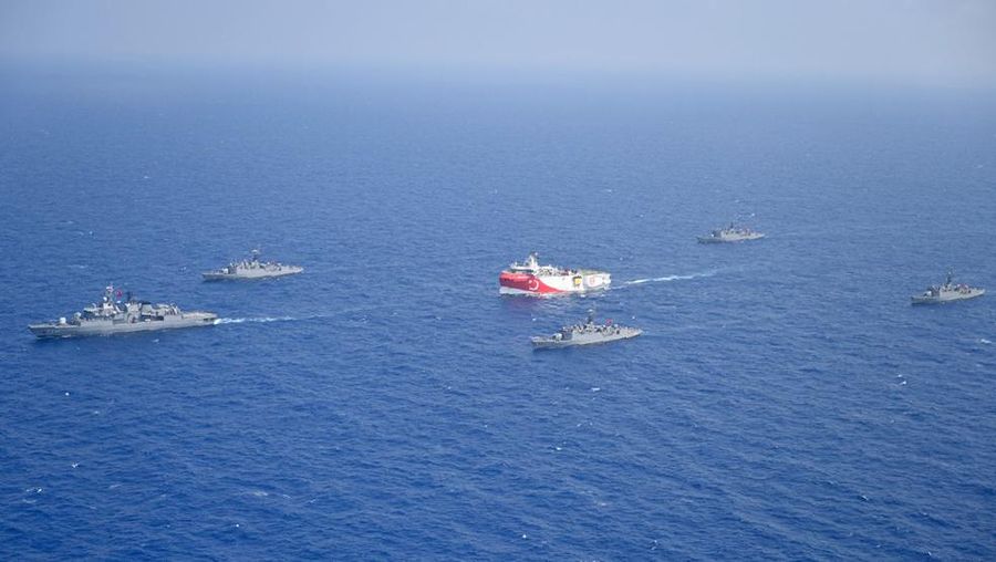 In this photo provided by the Turkish Defense Ministry, Turkey's research vessel, Oruc Reis, in red and white, is surrounded by Turkish navy vessels as it was heading in the west of Antalya on the Mediterranean, Turkey, Monday, Aug 10, 2020. Tension remains high between Greece and Turkey, whose warships are in the eastern Mediterranean where Turkey has sent a research vessel to carry out seismic research for energy resources in an area Greece says is on its continental shelf. (Turkish Defense Ministry via AP, Pool)