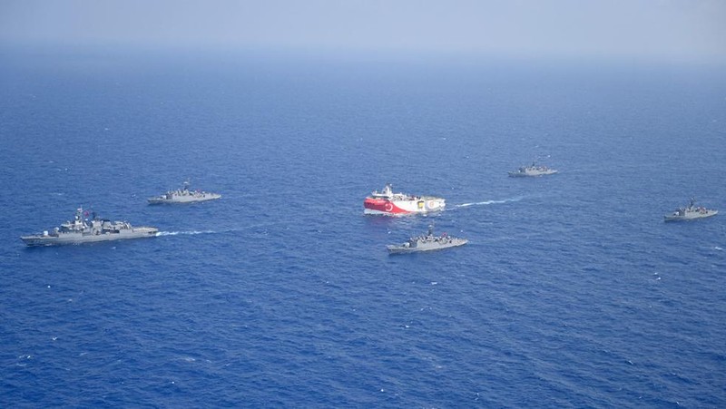 In this photo provided by the Turkish Defense Ministry, Turkey's research vessel, Oruc Reis, in red and white, is surrounded by Turkish navy vessels as it was heading in the west of Antalya on the Mediterranean, Turkey, Monday, Aug 10, 2020. Tension remains high between Greece and Turkey, whose warships are in the eastern Mediterranean where Turkey has sent a research vessel to carry out seismic research for energy resources in an area Greece says is on its continental shelf. (Turkish Defense Ministry via AP, Pool)