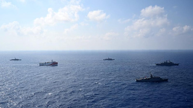 In this photo provided by the Turkish Defense Ministry, Turkey's research vessel, Oruc Reis, in red and white, is surrounded by Turkish navy vessels as it was heading in the west of Antalya on the Mediterranean, Turkey, Monday, Aug 10, 2020. Tension remains high between Greece and Turkey, whose warships are in the eastern Mediterranean where Turkey has sent a research vessel to carry out seismic research for energy resources in an area Greece says is on its continental shelf. (Turkish Defense Ministry via AP, Pool)