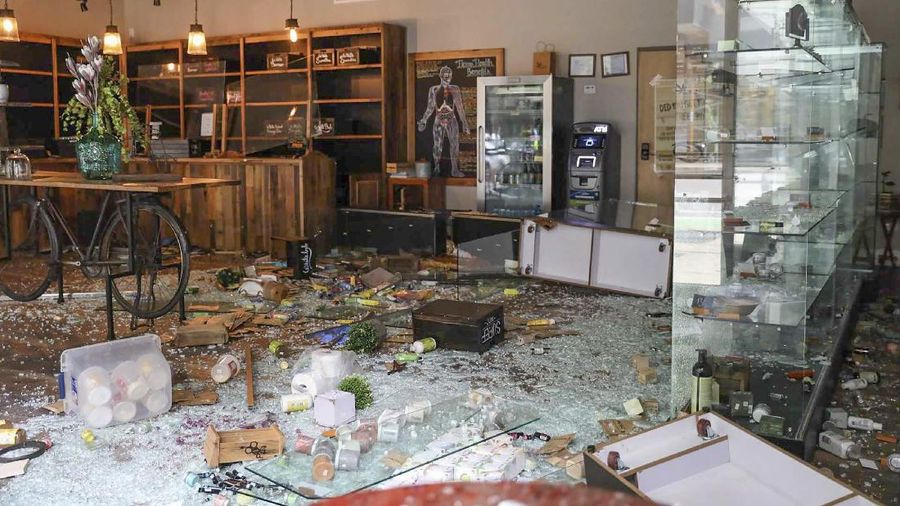 Kajal Dalal walks through her family's food and liquor store Monday, Aug. 10, 2020, after it was vandalized in downtown Chicago. Chicago’s police commissioner says more than 100 people were arrested following a night of looting and unrest that left several officers injured and caused damage in the city’s upscale Magnificent Mile shopping district and other parts of the city. (AP Photo/Charles Rex Arbogast)