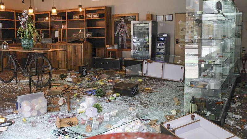 Kajal Dalal walks through her family's food and liquor store Monday, Aug. 10, 2020, after it was vandalized in downtown Chicago. Chicago’s police commissioner says more than 100 people were arrested following a night of looting and unrest that left several officers injured and caused damage in the city’s upscale Magnificent Mile shopping district and other parts of the city. (AP Photo/Charles Rex Arbogast)