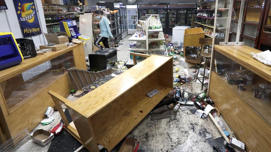 Kajal Dalal walks through her family's food and liquor store Monday, Aug. 10, 2020, after it was vandalized in downtown Chicago. Chicago’s police commissioner says more than 100 people were arrested following a night of looting and unrest that left several officers injured and caused damage in the city’s upscale Magnificent Mile shopping district and other parts of the city. (AP Photo/Charles Rex Arbogast)