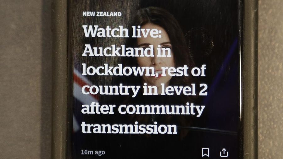 A news alert is displayed on a mobile phone in Christchurch, New Zealand, Tuesday, Aug. 11, 2020. New Zealand Prime Minister Jacinda Ardern said Tuesday that authorities have found four cases of the coronavirus in one Auckland household from an unknown source, the first cases of local transmission in the country in 102 days. (AP Photo/Mark Baker)