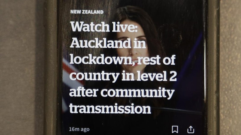 A news alert is displayed on a mobile phone in Christchurch, New Zealand, Tuesday, Aug. 11, 2020. New Zealand Prime Minister Jacinda Ardern said Tuesday that authorities have found four cases of the coronavirus in one Auckland household from an unknown source, the first cases of local transmission in the country in 102 days. (AP Photo/Mark Baker)