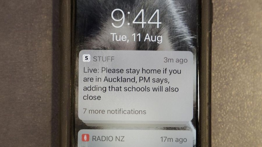 A news alert is displayed on a mobile phone in Christchurch, New Zealand, Tuesday, Aug. 11, 2020. New Zealand Prime Minister Jacinda Ardern said Tuesday that authorities have found four cases of the coronavirus in one Auckland household from an unknown source, the first cases of local transmission in the country in 102 days. (AP Photo/Mark Baker)
