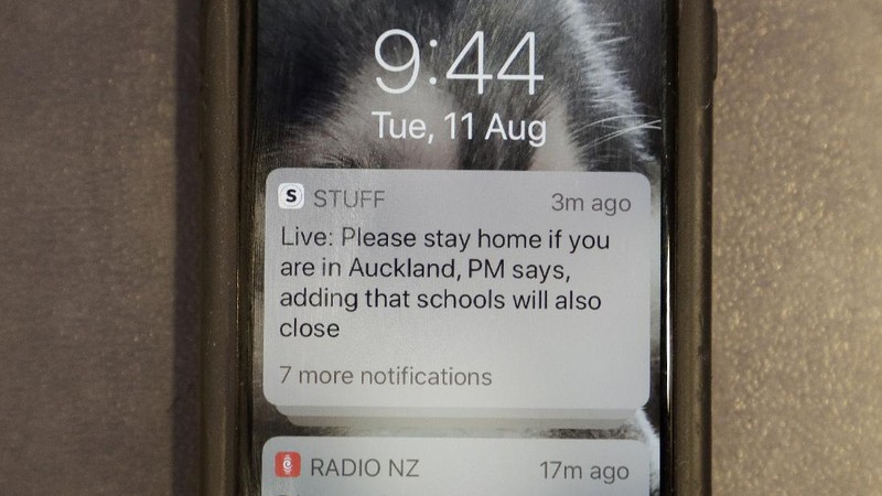 A news alert is displayed on a mobile phone in Christchurch, New Zealand, Tuesday, Aug. 11, 2020. New Zealand Prime Minister Jacinda Ardern said Tuesday that authorities have found four cases of the coronavirus in one Auckland household from an unknown source, the first cases of local transmission in the country in 102 days. (AP Photo/Mark Baker)