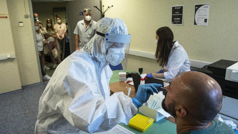 Petugas medis dengan alat pelindung mengambil darah para sukarelawan yang berpartisipasi dalam uji coba vaksin virus corona di Rumah Sakit Utama Militer Budenko di luar Moskow, Rusia.  (Russian Defense Ministry Press Service via AP)