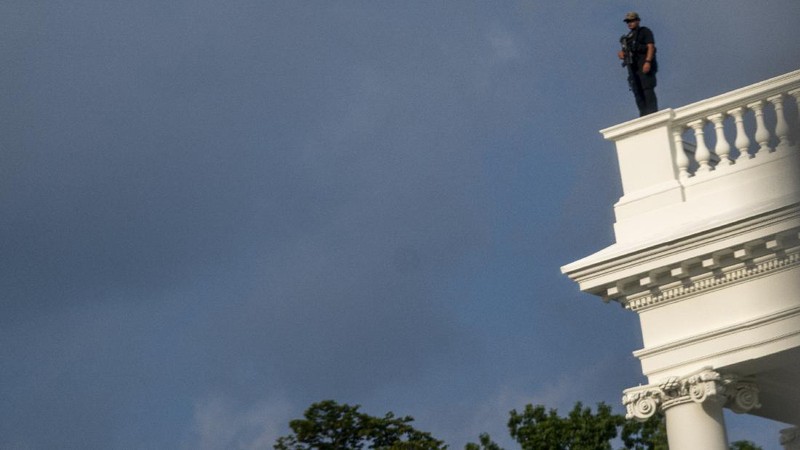A U.S. Secret Service police officer stands on the roof of the the White House, Monday, Aug. 10, 2020, in Washington, as a news conference by President Donald Trump was paused. (AP Photo/Andrew Harnik)