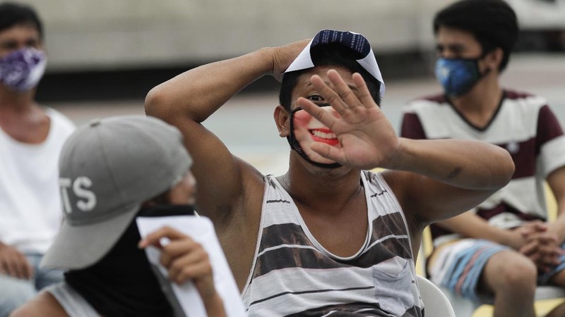 A man wearing a mask listens as they were rounded up by police at a public park for violating quarantine protocols in Quezon city, Philippines on Wednesday, Aug. 12, 2020. The residents were recorded and given lectures on community quarantine protocols before they were released as the capital and outlying provinces undergo another lockdown due to rising COVID-19 cases. (AP Photo/Aaron Favila)