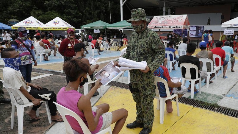 A man wearing a mask listens as they were rounded up by police at a public park for violating quarantine protocols in Quezon city, Philippines on Wednesday, Aug. 12, 2020. The residents were recorded and given lectures on community quarantine protocols before they were released as the capital and outlying provinces undergo another lockdown due to rising COVID-19 cases. (AP Photo/Aaron Favila)