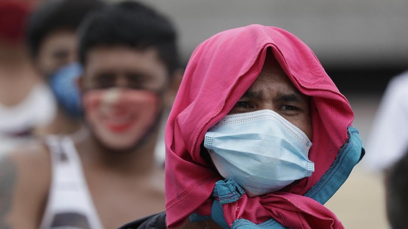 A man wearing a mask listens as they were rounded up by police at a public park for violating quarantine protocols in Quezon city, Philippines on Wednesday, Aug. 12, 2020. The residents were recorded and given lectures on community quarantine protocols before they were released as the capital and outlying provinces undergo another lockdown due to rising COVID-19 cases. (AP Photo/Aaron Favila)