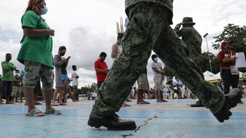 A man wearing a mask listens as they were rounded up by police at a public park for violating quarantine protocols in Quezon city, Philippines on Wednesday, Aug. 12, 2020. The residents were recorded and given lectures on community quarantine protocols before they were released as the capital and outlying provinces undergo another lockdown due to rising COVID-19 cases. (AP Photo/Aaron Favila)