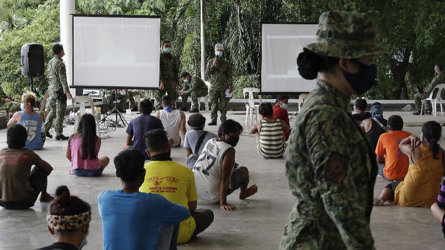 A man wearing a mask listens as they were rounded up by police at a public park for violating quarantine protocols in Quezon city, Philippines on Wednesday, Aug. 12, 2020. The residents were recorded and given lectures on community quarantine protocols before they were released as the capital and outlying provinces undergo another lockdown due to rising COVID-19 cases. (AP Photo/Aaron Favila)