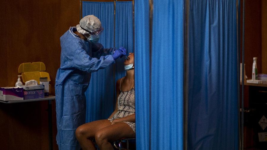 Spanish NGO Open Arms volunteer,  Julia Martin, 38, plays with 4-month old Biel, as his father takes a COVID-19 PCR test, at Vilafranca del Penedes in the Barcelona province, Spain, Tuesday, Aug. 11, 2020. Spain is facing another surge in coronavirus infections not even two months after beating back the first wave. (AP Photo/Emilio Morenatti)