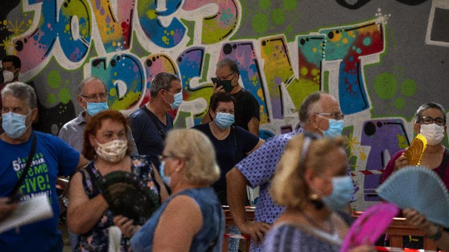 Spanish NGO Open Arms volunteer,  Julia Martin, 38, plays with 4-month old Biel, as his father takes a COVID-19 PCR test, at Vilafranca del Penedes in the Barcelona province, Spain, Tuesday, Aug. 11, 2020. Spain is facing another surge in coronavirus infections not even two months after beating back the first wave. (AP Photo/Emilio Morenatti)