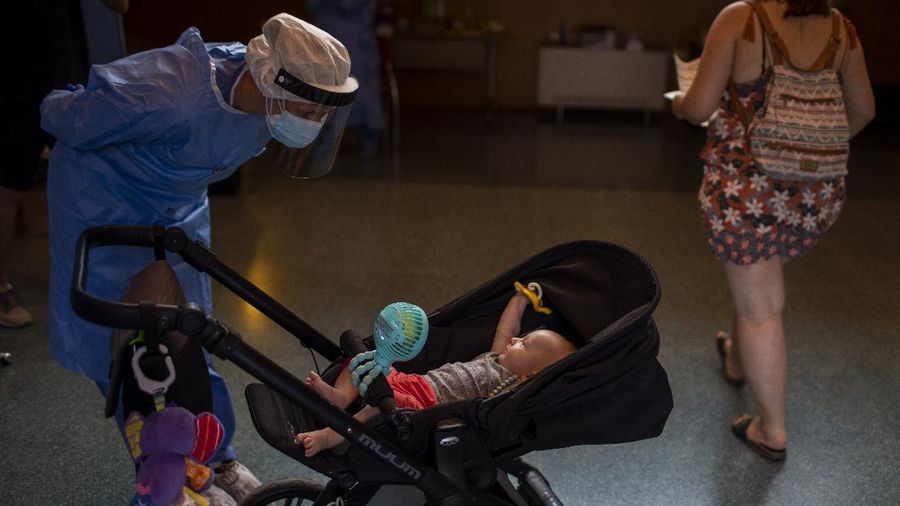 Spanish NGO Open Arms volunteer, Julia Martin, 38, plays with 4-month old Biel, as his father takes a COVID-19 PCR test, at Vilafranca del Penedes in the Barcelona province, Spain, Tuesday, Aug. 11, 2020. Spain is facing another surge in coronavirus infections not even two months after beating back the first wave. (AP Photo/Emilio Morenatti)