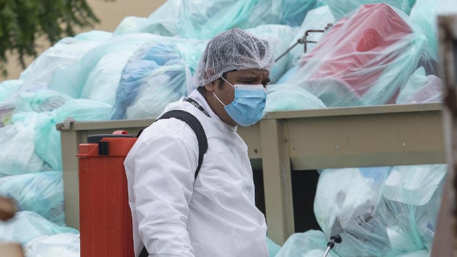 Medical workers using protective equipment dispose of trash bags containing hazardous biological waste into a large pile outside the Hospital del Instituto Mexicano del Seguro Social, which treats patients with COVID-19 in Veracruz, Mexico, Wednesday, Aug. 12, 2020. Improper disposal of medical waste has become an increasing problem in Mexico amid the pandemic. (AP Photo/Felix Marquez)