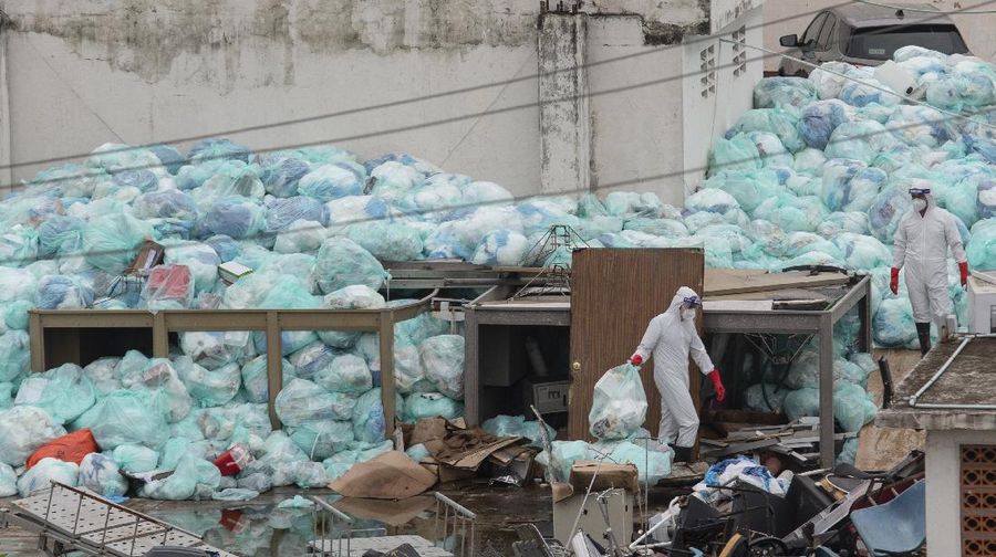 Medical workers using protective equipment dispose of trash bags containing hazardous biological waste into a large pile outside the Hospital del Instituto Mexicano del Seguro Social, which treats patients with COVID-19 in Veracruz, Mexico, Wednesday, Aug. 12, 2020. Improper disposal of medical waste has become an increasing problem in Mexico amid the pandemic. (AP Photo/Felix Marquez)