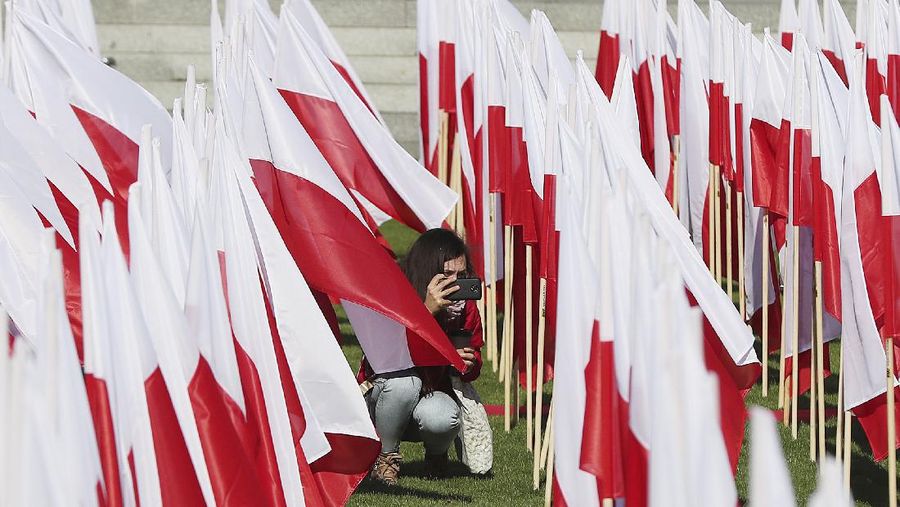 A girl takes photos of Poland's national flags arranged artistically at a popular location to mark The Day of the National Flag, in Warsaw, Poland, Saturday, May 2, 2020.(AP Photo/Czarek Sokolowski)