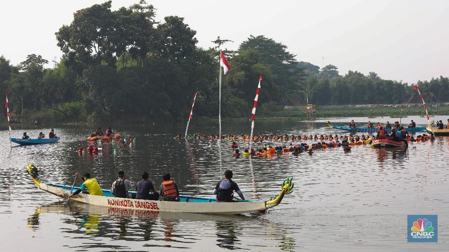 Petugas pengibar bendera melakukan pengibaran bendera Merah Putih pada peringatan HUT Kemerdekaan ke-75 RI di tengah Situ 7 Muara Pamulang, Tangerang Selatan, Banten, Senin (17/8/2020). Upacara yang diikuti oleh ratusan aktivis lingkungan hidup dan juga organisasi kepemudaan iini bertujuan agar pemerintah terus menjaga keberadaan situ yang ada di manapun. (CNBC Indonesia/ Andrean Kristianto)