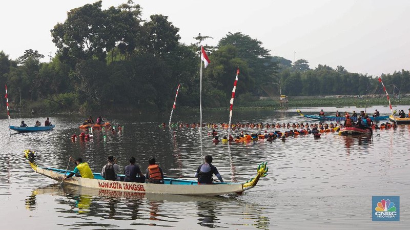 Petugas pengibar bendera melakukan pengibaran bendera Merah Putih pada peringatan HUT Kemerdekaan ke-75 RI di tengah Situ 7 Muara Pamulang, Tangerang Selatan, Banten, Senin (17/8/2020). Upacara yang diikuti oleh ratusan aktivis lingkungan hidup dan juga organisasi kepemudaan iini bertujuan agar pemerintah terus menjaga keberadaan situ yang ada di manapun. (CNBC Indonesia/ Andrean Kristianto)