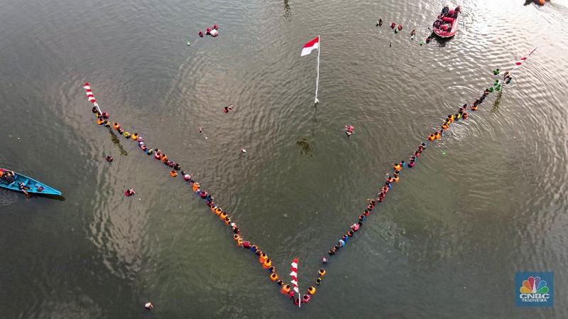 Petugas pengibar bendera melakukan pengibaran bendera Merah Putih pada peringatan HUT Kemerdekaan ke-75 RI di tengah Situ 7 Muara Pamulang, Tangerang Selatan, Banten, Senin (17/8/2020). Upacara yang diikuti oleh ratusan aktivis lingkungan hidup dan juga organisasi kepemudaan iini bertujuan agar pemerintah terus menjaga keberadaan situ yang ada di manapun. (CNBC Indonesia/ Andrean Kristianto)