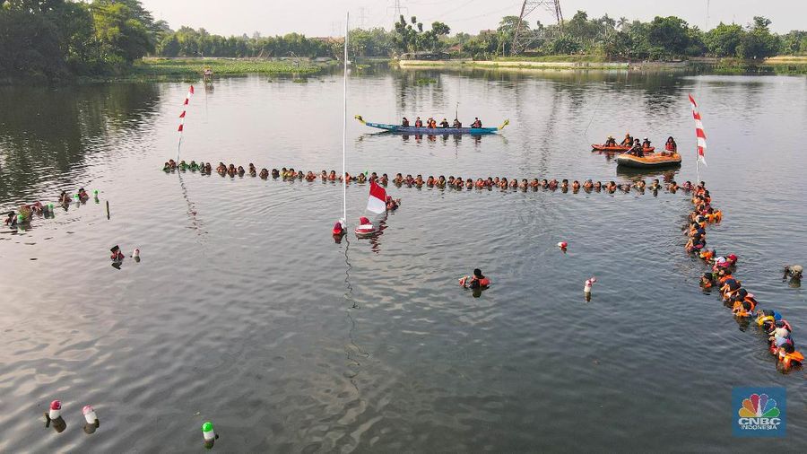 Petugas pengibar bendera melakukan pengibaran bendera Merah Putih pada peringatan HUT Kemerdekaan ke-75 RI di tengah Situ 7 Muara Pamulang, Tangerang Selatan, Banten, Senin (17/8/2020). Upacara yang diikuti oleh ratusan aktivis lingkungan hidup dan juga organisasi kepemudaan iini bertujuan agar pemerintah terus menjaga keberadaan situ yang ada di manapun. (CNBC Indonesia/ Andrean Kristianto)