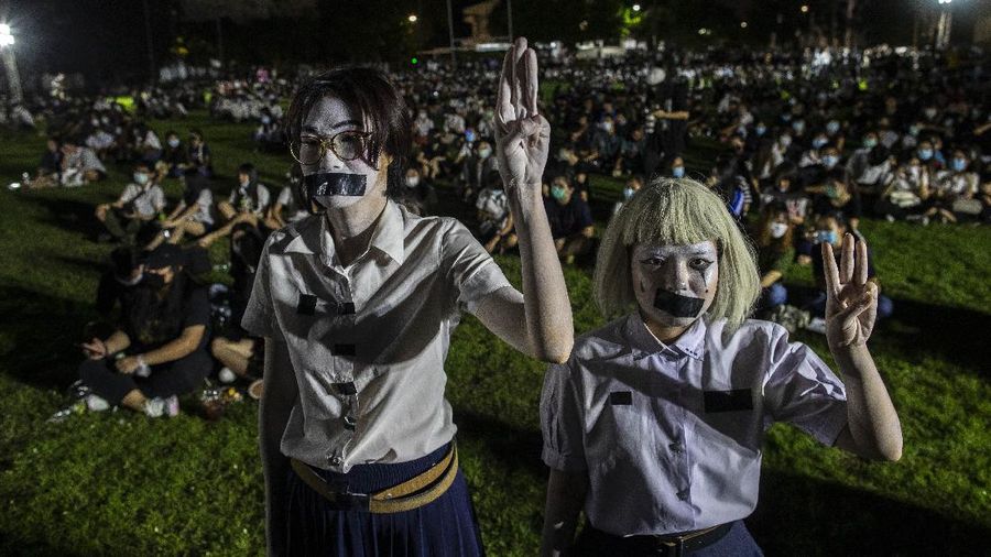 Pro-democracy students with tapes covering their mouths raise a three-fingers, symbol of resistance salute during a protest rally at Mahidol University in Nakhan Pathom, Thailand, Tuesday, Aug. 18, 2020. Student protesters have stepped up pressure on the government with three core demands: holding new elections, amending the constitution and ending the intimidation of critics of the government. (AP Photo/Gemunu Amarasinghe)