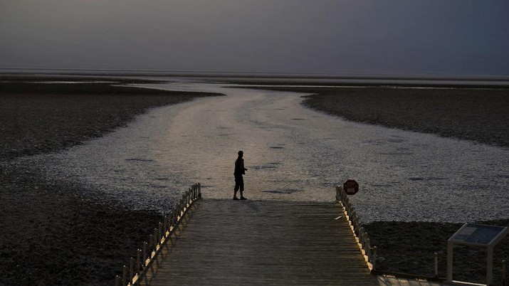 A person walks on a boardwalk at the salt flats at Badwater Basin, Monday, Aug. 17, 2020, in Death Valley National Park, Calif. Death Valley recorded a scorching 130 degrees (54.4 degrees Celsius) Sunday, which if the sensors and other conditions check out, would be the hottest Earth has been in more than 89 years and the third-warmest ever measured. (AP Photo/John Locher)