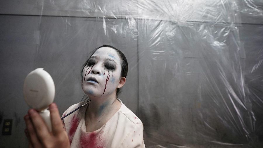 Casts as zombies perform by the window of a vehicle during a demonstration of a drive-in haunted house show at a garage Tuesday, Aug. 18, 2020, in Tokyo. Visitors remain in vehicles as taking prevention measures against the COVID-19 pandemic, while ghosts, zombies and other characters spook the visitors. Visitors could experience the entertainment with the safety of being inside their own vehicles. Or, a vehicle provided by the program is also available for rent at the site. (AP Photo/Eugene Hoshiko)