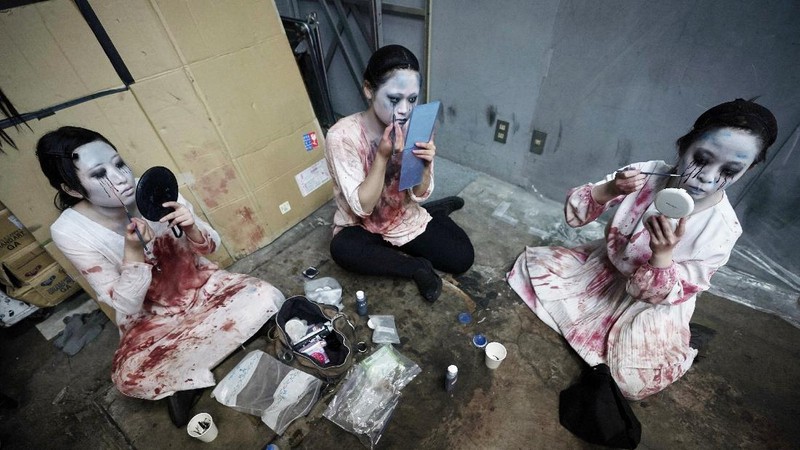 Casts as zombies perform by the window of a vehicle during a demonstration of a drive-in haunted house show at a garage Tuesday, Aug. 18, 2020, in Tokyo. Visitors remain in vehicles as taking prevention measures against the COVID-19 pandemic, while ghosts, zombies and other characters spook the visitors. Visitors could experience the entertainment with the safety of being inside their own vehicles. Or, a vehicle provided by the program is also available for rent at the site. (AP Photo/Eugene Hoshiko)